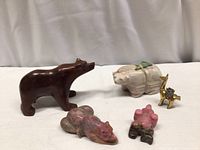 Five animal figurines including bears and a camel arranged on a white surface with draped background.