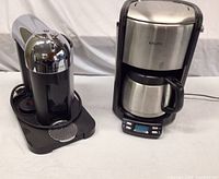 Nespresso CitiZ espresso machine and Krups drip coffee maker side by side on white background.