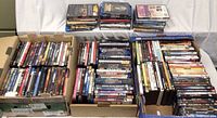 Image shows the entire large lot of DVDs and Blu-ray discs arranged in cardboard boxes and stacks, giving an overview of the collection size and condition.