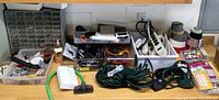 Wide view of assorted hardware, cords, power strips, and organizers on table with small tools, glue bottle, and electrical items visible.