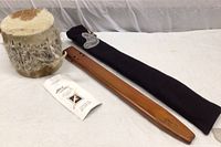 Flute, drum and documentation laid on white cloth, showing the drum's natural hide surface and the carved wooden flute with carrying case.