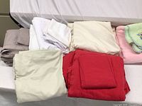 All sheets and blankets visible including folded sheets in white, cream, beige, burgundy, and pink baby blankets on right side.