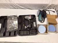 Closed case containing Senco SL818 pneumatic stapler and manual with Senco premium staples pack next to it; Bosch disc sander and two open boxes of blue sanding discs next to the case.