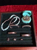 Mixed turquoise chip bead necklace, bracelets, rings and green jewelry box on black velvet tray