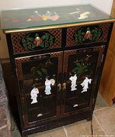 Full view of vintage black lacquer Japanese cabinet with painted and inlaid decoration on front.