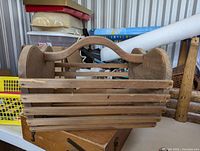 Front view of the rectangular wood apple hod basket showing horizontal slats and arched handle span across the top