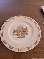 Bone china plate with Bunnykins illustration showing rabbits in a camp scene and border of bunny motifs.