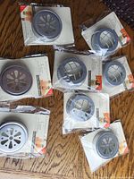 19 Mason jar lids displayed on wooden surface, showing two distinct cutout designs (flower and grid). All lids are new and individually packaged.