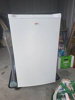 Closed view of white Koolatron compact upright mini freezer with brand label on door.