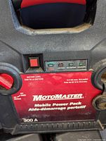 Close-up front of MotoMaster Mobile Power Pack portable car battery charger in red and black, showing brand and battery level indicator with 300A rating.