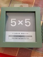 Front view of the square green Studio Decor picture frame sized 5x5 inches, showing product details and glass front.
