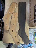 Top-down view of three wooden stretchers, two light wood with multiple circular holes and one dark wood paddle-shaped.