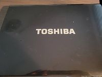 Closed black Toshiba laptop showing Toshiba logo on the lid.