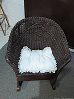 Front view of brown wicker doll rocking chair with white cushion on seat.