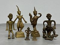 Front view of six brass figurines including two Thai-style and four abstract figures, showing detailing and condition