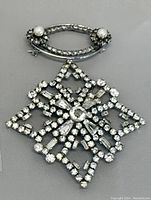 Photo of brooch showing oval loop with pearls and cross-shaped rhinestone design