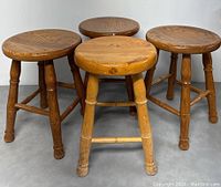 Four vintage solid wood stools shown from side, front, and top views, showing the round seats, turned legs, and stretcher supports.