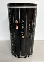 Front view showing black ceramic surface with white calligraphy writing and red seals.