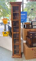 Front view of the wooden display cabinet showing glass door and shelves inside.