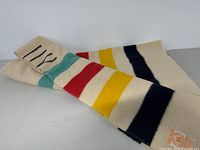 Cream wool Hudson's Bay blanket laid flat showing multicolor stripes including teal, red, yellow, and navy.