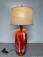 Full view of MCM ceramic table lamp front with plugged cord and beige patterned drum shade