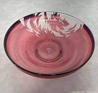 Top view of translucent pink art glass bowl showing etched exterior designs.