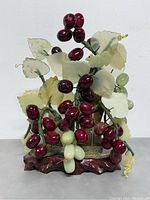 Front view of the bonsai tree showing dark red glass grapes, pale green glass grapes, and jade leaves on carved wooden base.