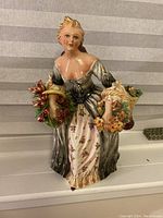 Front view of the woman figurine showing detailed dress and flower wreaths