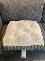 Top Paw dog bed placed on a dark textured couch showing the cream tufted top and padded beige sides.