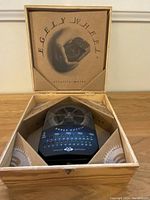 Opened wooden box containing Egely Wheel Vitality Meter with transparent cover and LED indicators, showing device and packaging.