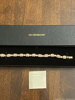 Full length of gold bonded sterling silver bracelet with pink and clear stones in black velvet box with Technibond branding.