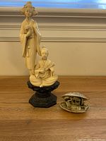 Photo showing Japanese-style figurine and shell diorama together on a wooden surface