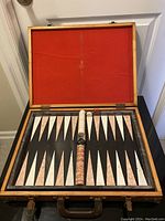 Open backgammon game set with black and grey marble board, white and brown marble pieces, red dice, and doubling cube in center with vintage wood case lined in red felt.