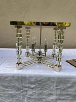 Full view of the light fixture showing chrome frame, acrylic cubes, and four candle-style bulbs.