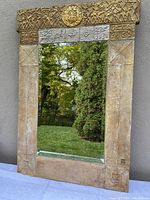 Full view of the large rectangular mirror showing the entirety of the textured gold and silver frame with sun medallion and symbolic engravings.