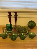 Full lot view showing two red glass candle holders, green votive, green relish dish, four green tea light holders, green glass ball and Italian tray on wooden surface.