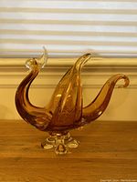 Front angle view of amber glass rooster bowl showing curved wings and tail, small chip on comb