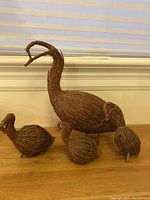 View of the four twig partridge family sculptures arranged on a shelf with a white wall background