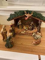 Full nativity scene with wooden stable, nine total figurines, and straw bedding