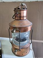 Front angled view showing the copper ship's lantern featuring a glass middle and metal handle on top with visible electrical cord.