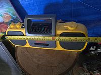 Front-facing view of the yellow Sony Sports CFS-905 Mega Bass boombox on a wooden surface with measuring tape showing approx 18 inches in length.
