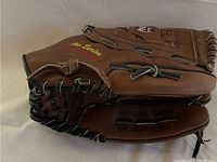 Side angle showing exterior of brown leather baseball glove with yellow "Pro Series" embroidered, black rawhide lacing.