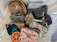 Nine assorted child and teen purses including two Cath Kidston floral crossbody bags and various other designs such as a sequin pouch, an orange slice circular bag, and a taupe backpack purse with flower embroidery.