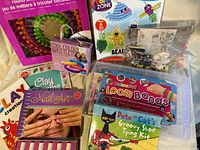 Photo showing Nail Art book, Clay Creation books, Cool Colour Wristlet set, bead key chain sets, Loom Bands kit, and Pete the Cat Groovy Shoe Tying Kit with several used nail polish bottles.