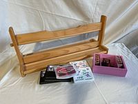 Wooden IKEA paper dispenser with a roll holder, Melissa & Doug wooden stamps, and black, pink, purple ink pads all placed together on a mattress.