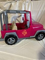 Side view of pink and silver plastic Jeep toy, showing decal, seating, and roll bar.