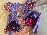 Rapunzel costume dress with puff sleeves, pink skirt, clear glasses, pink purse, and assorted children's jewelry