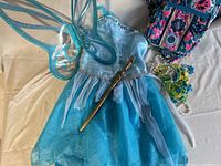 Blue child's Tinkerbell costume dress with sparkly silver trim, homemade wand, patterned play purse, and assorted costume jewelry