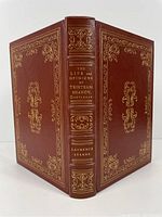 Front view of the book showing full brown leather cover with gold embossed floral and ornamental designs on front, back, and spine.