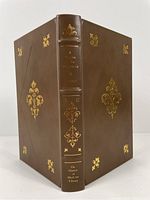 Front view of the book showing full leather brown cover with gold gilt decorative detailing on the cover and spine.